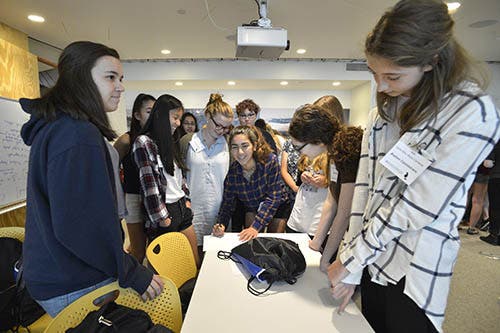 A photo of a group of girls standing around a table.
