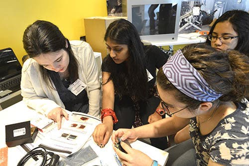 A photo of a group of girls working on building a camera together.