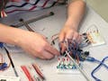 A collaged image of various electronic prototype designs and classroom scenes from the 2017 MIT IAP Arduino class.