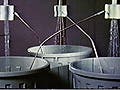 Top: A photograph of two streams of water running into buckets and producinng DC current. Bottom: A photograph of a three-stream water running system that produces AC current.