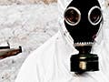 A photograph of a person wearing a hazmat suit and holding a radiation detector, and standing in front of a banner landscape with a destroyed object in the background.