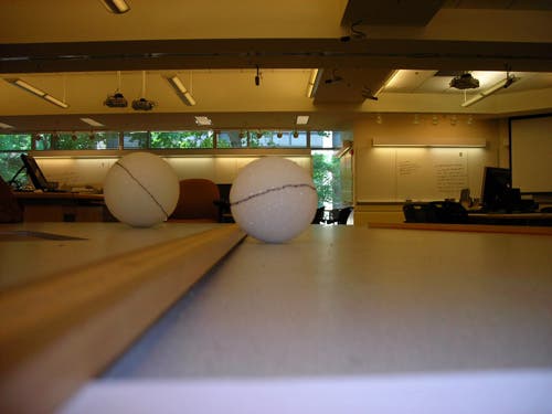A close-up photo of two balls being measured with rulers. 