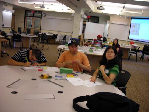 An image of three students working at a table using modeling clay. 