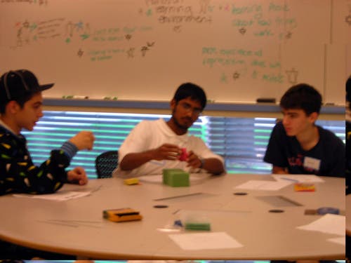 Photo of three students sitting at  table using modeling clay. 