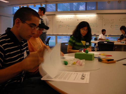 An image of three students working at a table using modeling clay. 