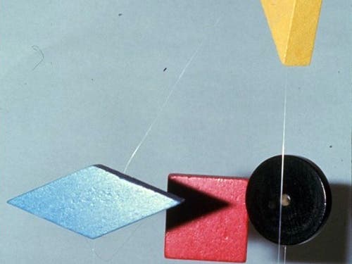 A photo of a mobile consisting of wooden blocks: a blue diamond, red square, black circle, and a yellow triangle. 