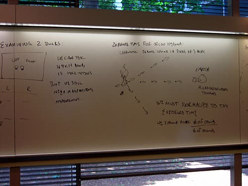 Handwritten notes on a whiteboard about flux exposure time. 