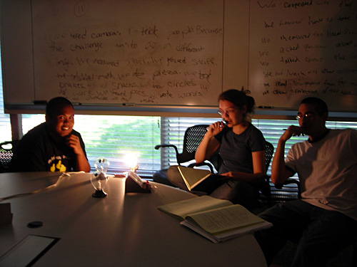 Three students sit at a table looking at a radiometer, which is a device that measure radiant flux. 