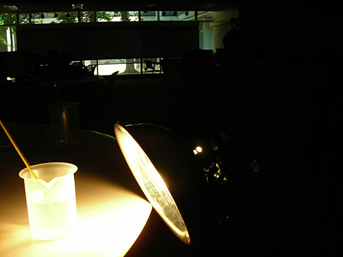 A photo of a beaker of water with a bright light shining on it. 