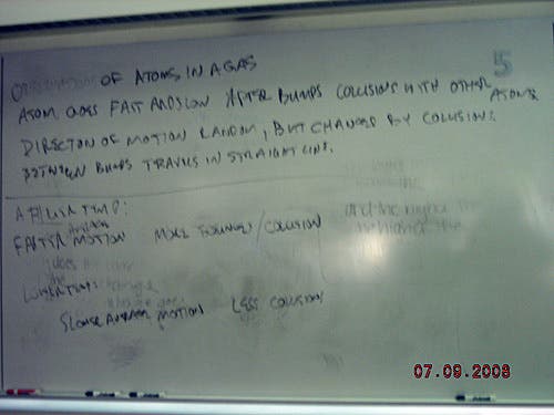 Handwritten notes on a whiteboard about observations of atoms in a gas. 