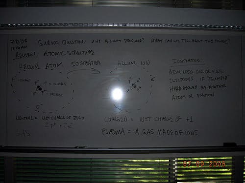 Handwritten notes on a whiteboard about atomic structure. 