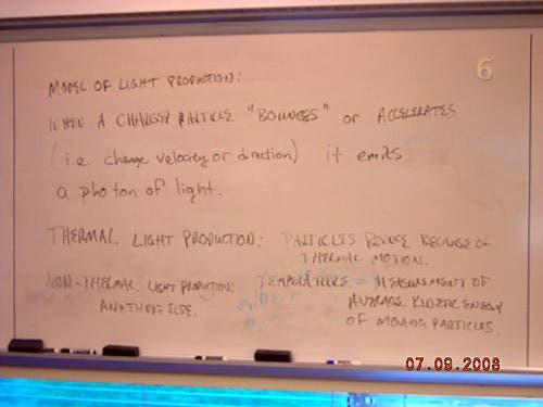 Handwritten notes on a whiteboard about the model of light production. 