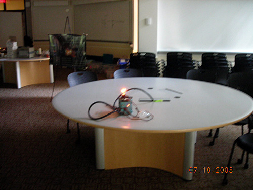 A photo of a demonstration of the brightness of a bulb. A very bright glowing lightbulb sits on a round table