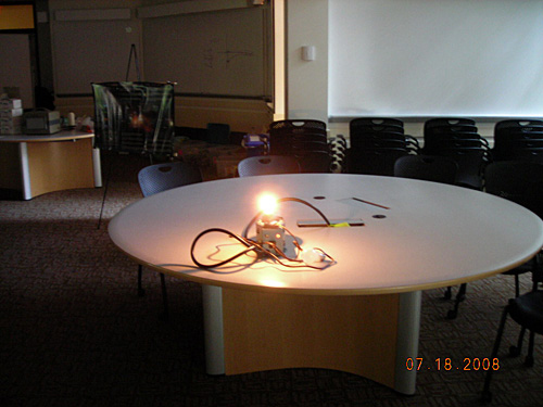 A photo of a demonstration of the brightness of a bulb. A very bright glowing lightbulb sits on a round table