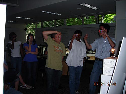 A photo of the instructor with some students holding up small squares practicing the concept of cross dispersion