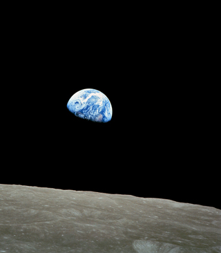 Photo of the earth appearing to rise over the surface of the moon.