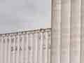 A photo of two rows of tall concrete grain elevators with a few railroad cars.