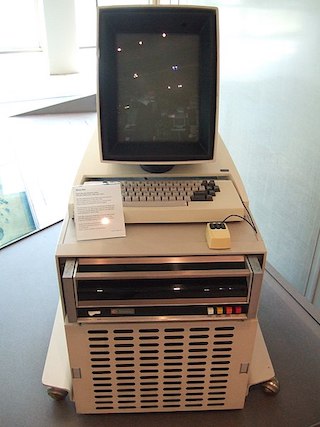 Photograph of early computer with keyboard and monitor.