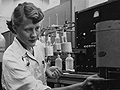Black and white photo of a young woman working in a chemistry lab.