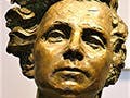  A bronze bust of a woman with strong features and wavy hair.