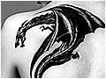 A black and white photograph of a large dragon tattoo on a woman's back.