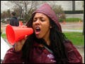 A woman shouts through a megaphone while holding a banner that says "Women's Rights=Human Rights."