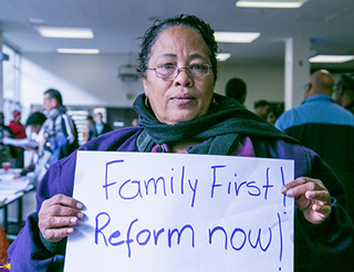 A woman holds up a sign that reads "Family First! Reform now!"