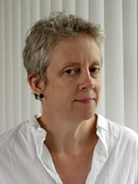 A headshot of a woman wearing a white shirt with short grey hair. 